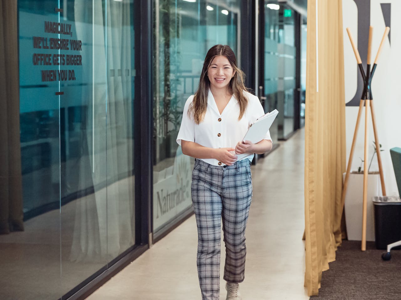 vrouw die een geruite broek draagt ​​en documenten vasthoudt tijdens het lopen
