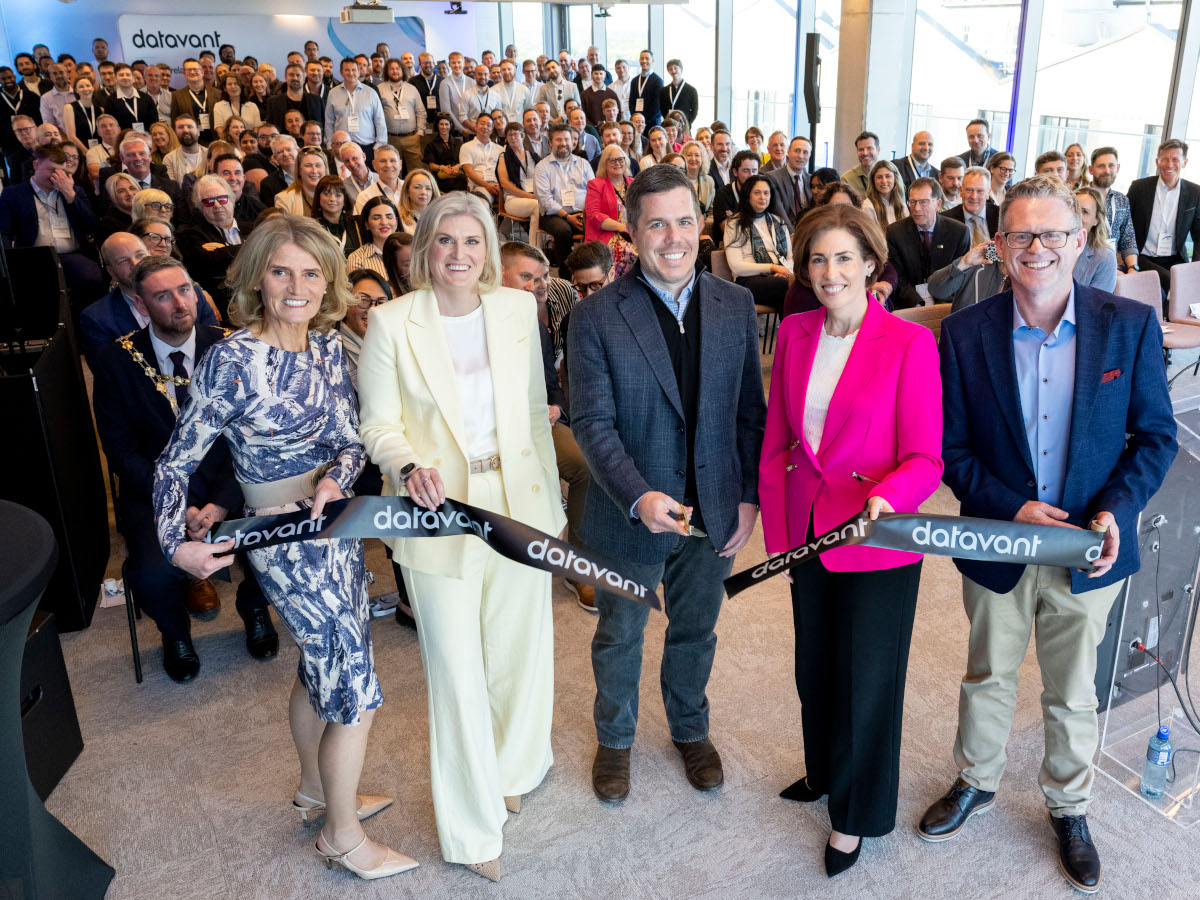 Datavant and government representatives cutting a black ribbon in front of a large crowd.